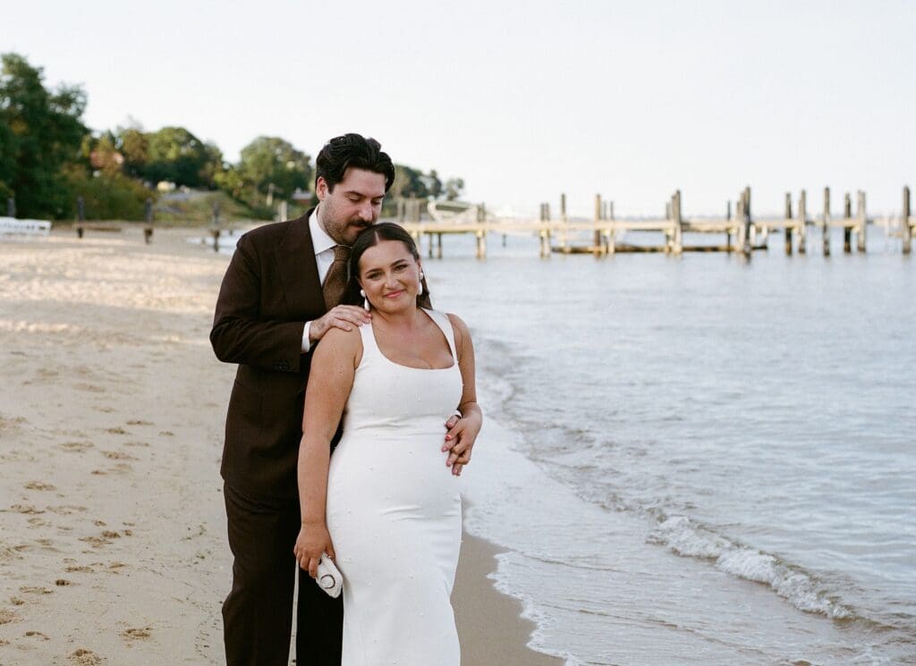 Bride and groom posing on the beach for their wedding portraits