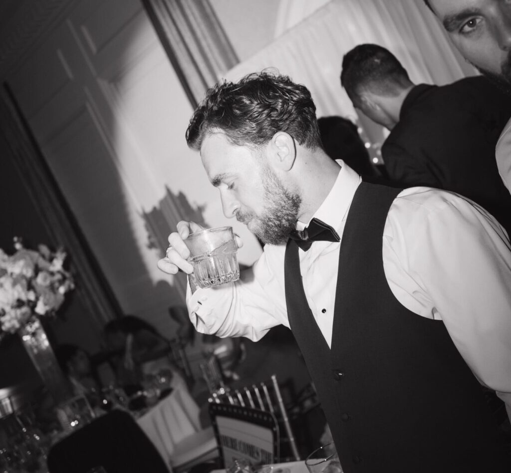 Groomsmen drinking from a glass at a wedding reception
