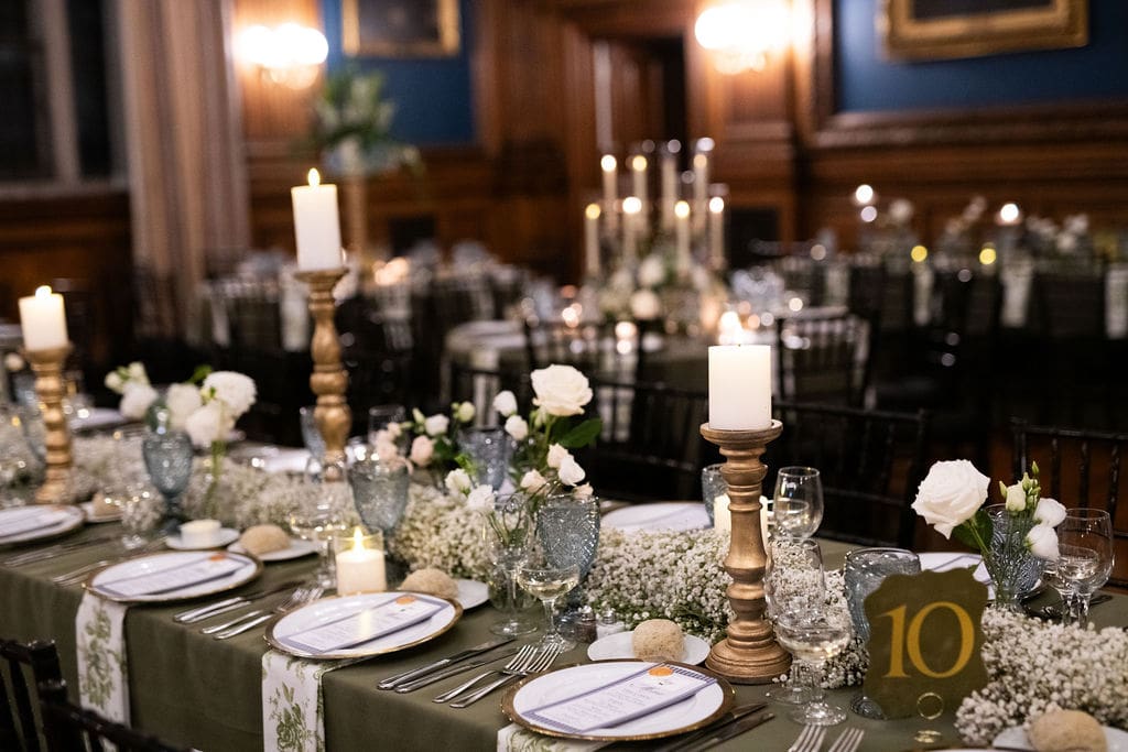 Wedding reception table with candles, florals, table number, and various dining details