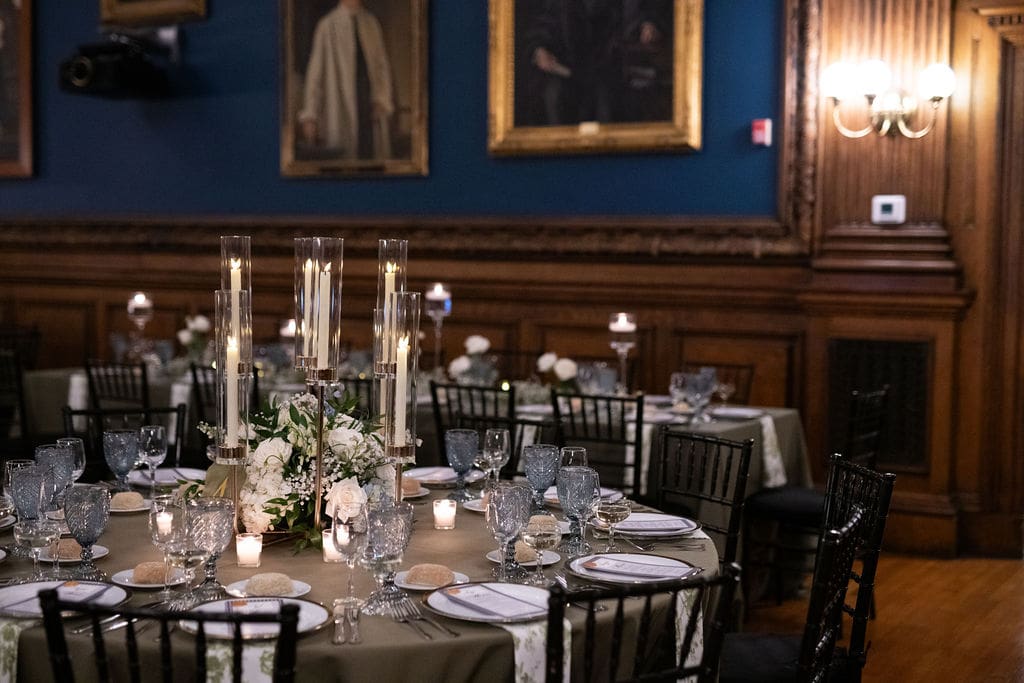 Elegant wedding reception tables with candles, florals, plates, and napkins