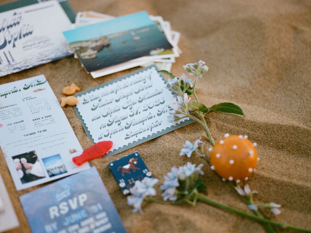 Beach-themed wedding stationery layered for a flatlay on the beach